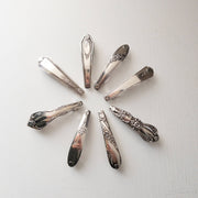 Eight vintage silver-toned ornate hair clips arranged in a circular pattern on a white background.
