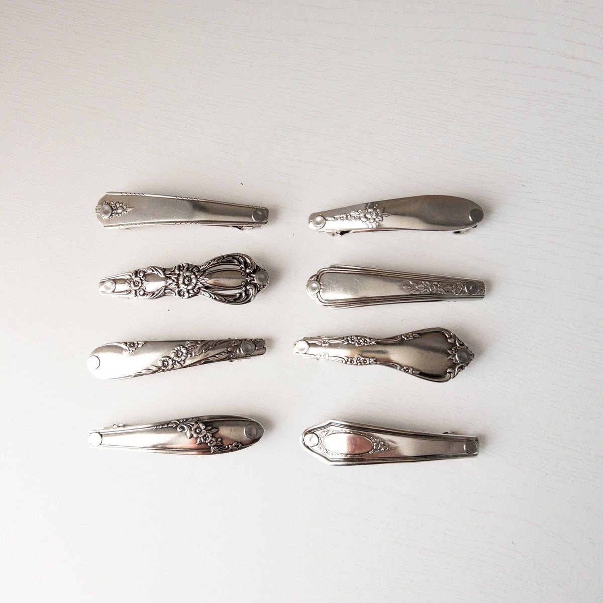 Eight vintage silver-toned floral engraved hair clips on a white background