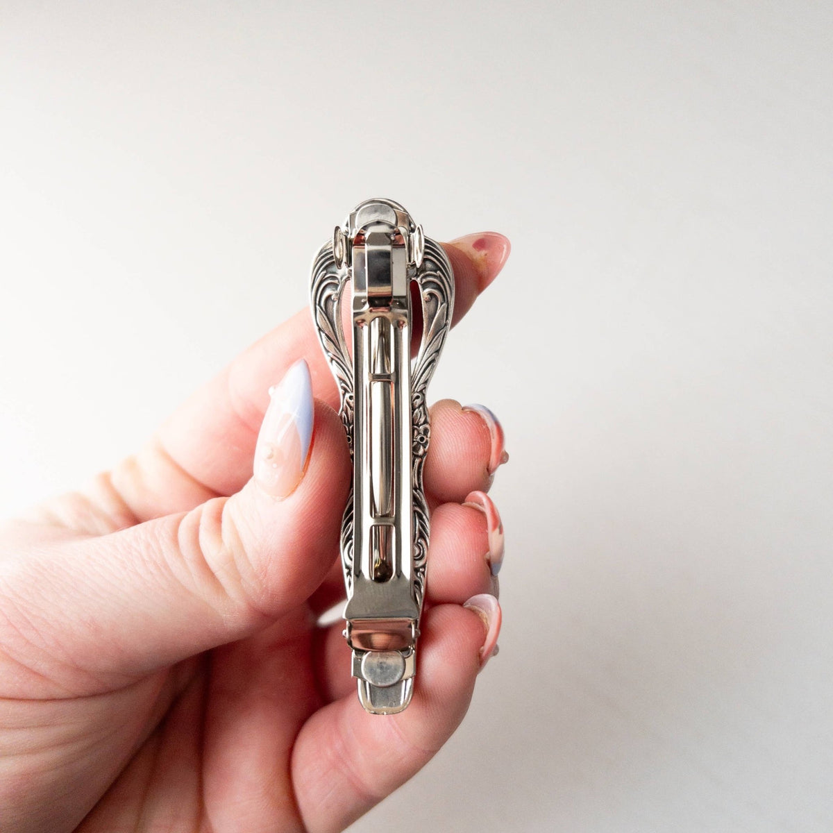 Close-up of a hand holding an ornate silver vintage-style hair clip